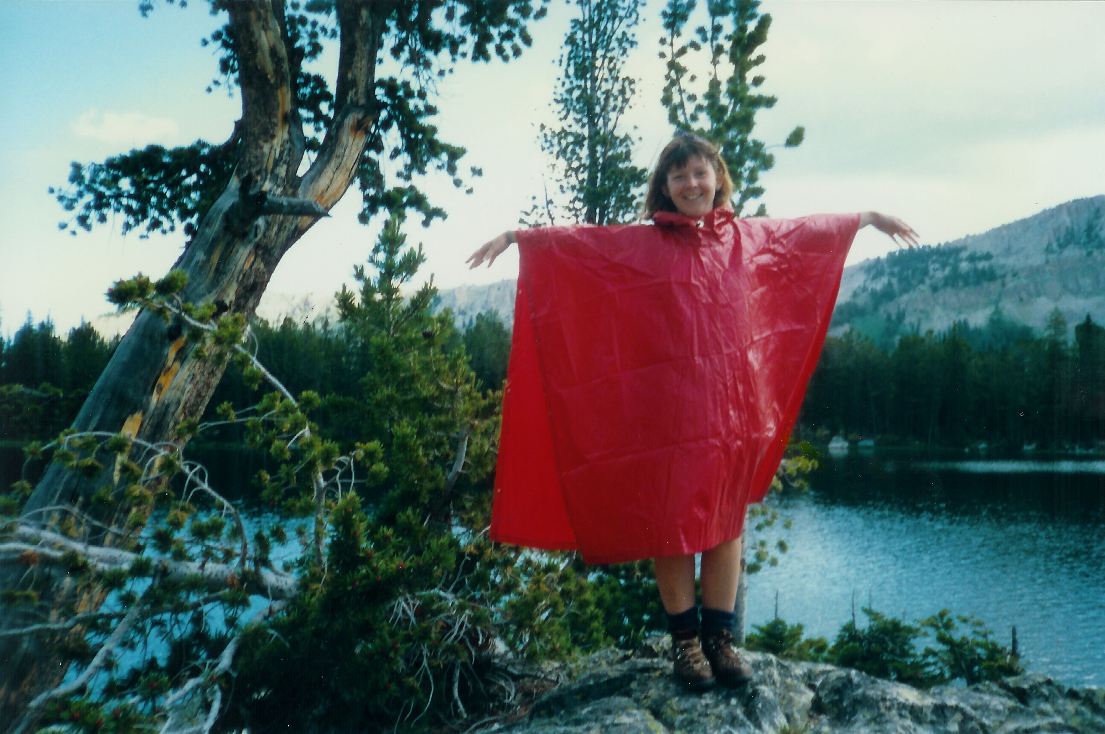 Photo of DJ Choupin in a red cape by a high mountain lake in 1980s Jackson Hole