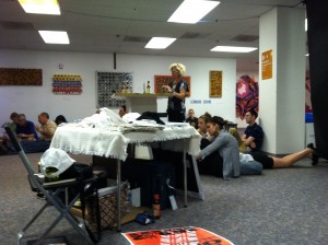 Photo of sprawling room only at the workshop concert performance of A Roadkill Opera on June 9, 2012. Production assistant Nina Ganz can be seen at the center of the spillover crowd, behind the table of swag.