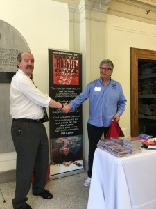 Photo of Durnan and Parker shaking hands in front of Durnan's office and Parker's pop-up banner