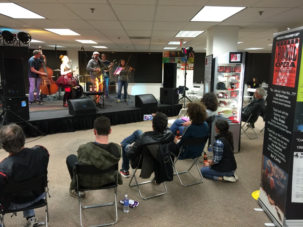 Photo of audience sitting by Parker's exhibit and watching a bluegrass band perform at Artomatic 2015