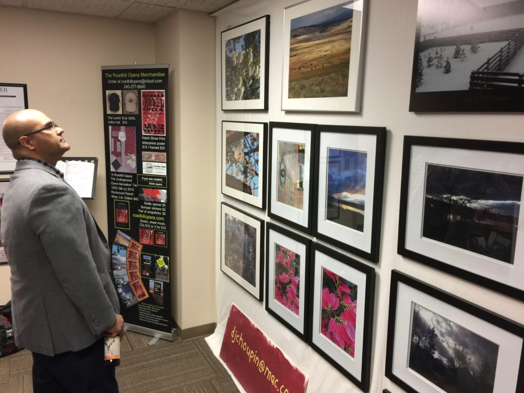 Photo of a man looking at DJ Choupin's photos at Artomatic 2017 in Crystal City, Virginia